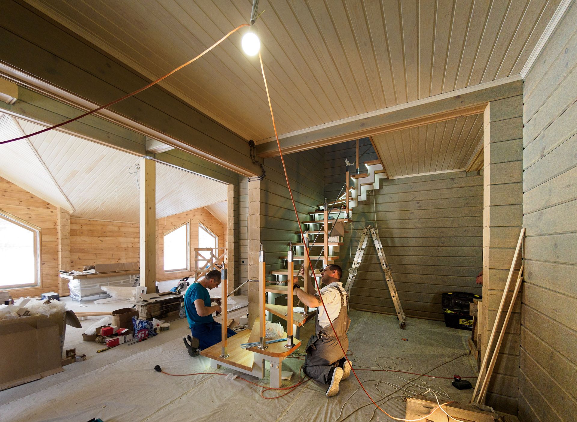 Carpenters skillfully assembling a modern wooden staircase inside a newly constructed home interior.